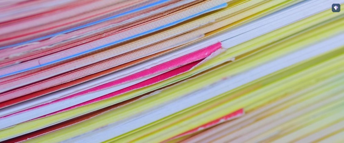 A deep stack of papers in many colours seen edge on