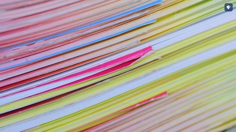 A deep stack of papers in many colours seen edge on