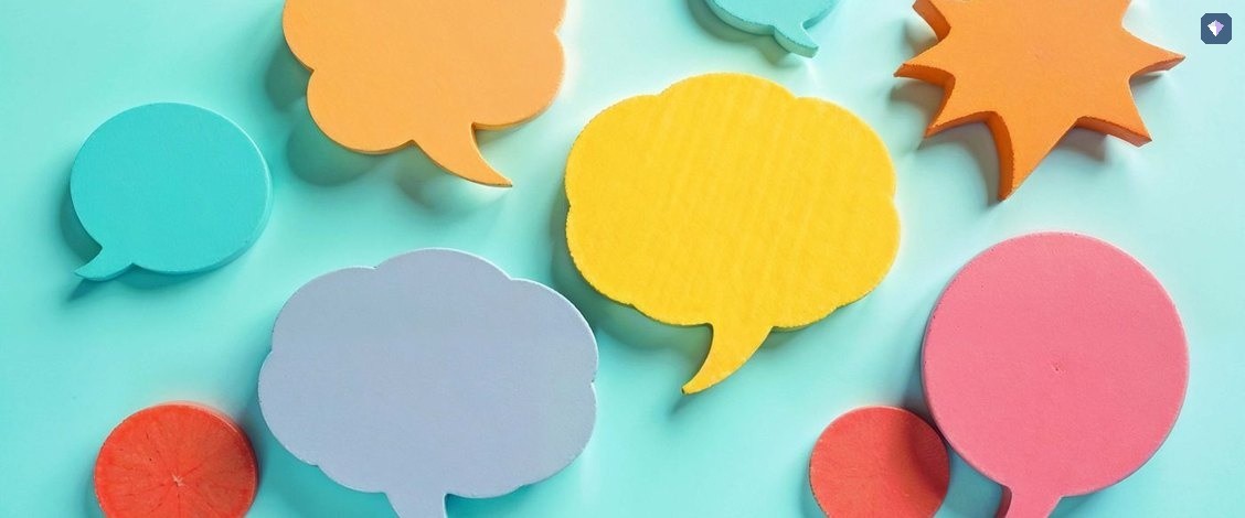 Paper speech bubbles in bright colours laid out on a turquoise background