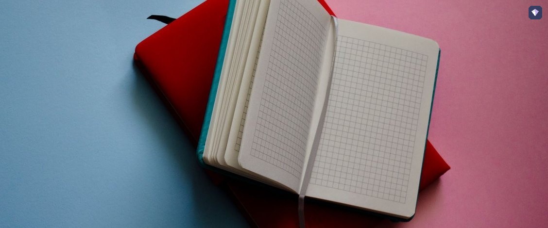An open notebook with blank pages on a pink and blue background