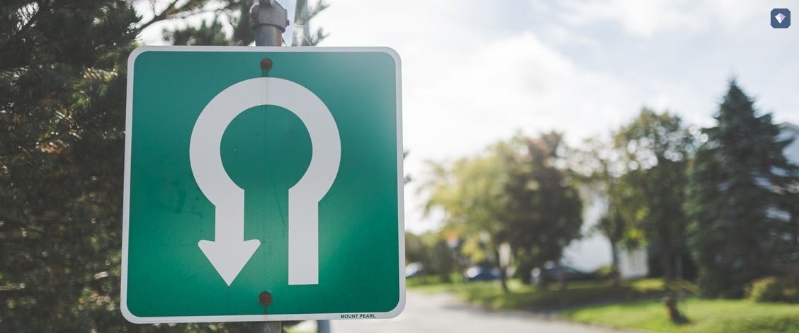 A green road sign carrying a U turn arrow at the roadside