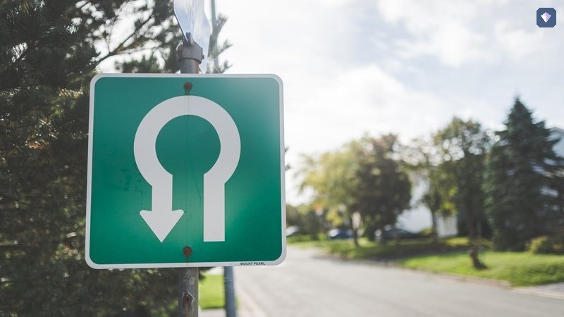 A green road sign carrying a U turn arrow at the roadside