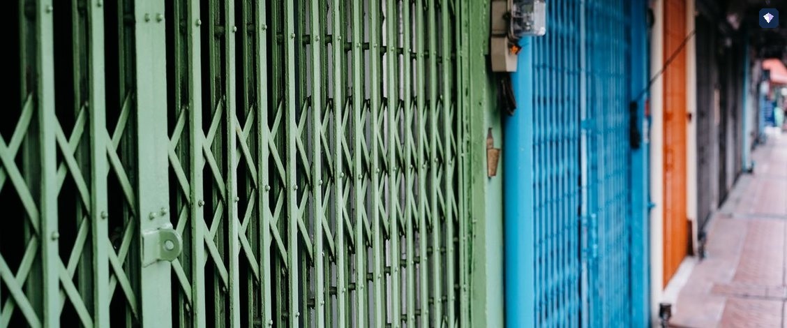 A run of painted metal shutters closed along an alleyway
