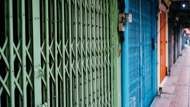 A run of painted metal shutters closed along an alleyway