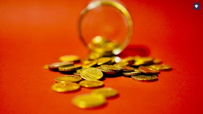 Gold coins spilling from a glass jar onto a red background