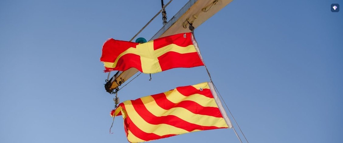Red and yellow signal flags flying against a clear blue sky