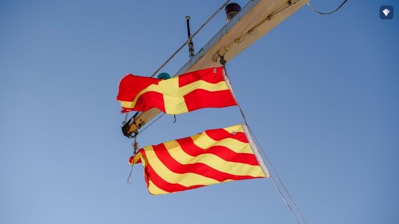 Red and yellow signal flags flying against a clear blue sky