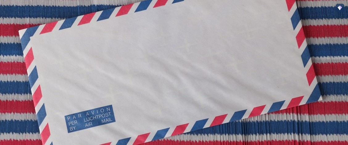 An airmail envelope lying on a red, white and blue striped surface