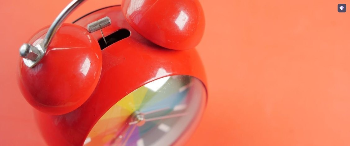 A red alarm clock standing on an orange background