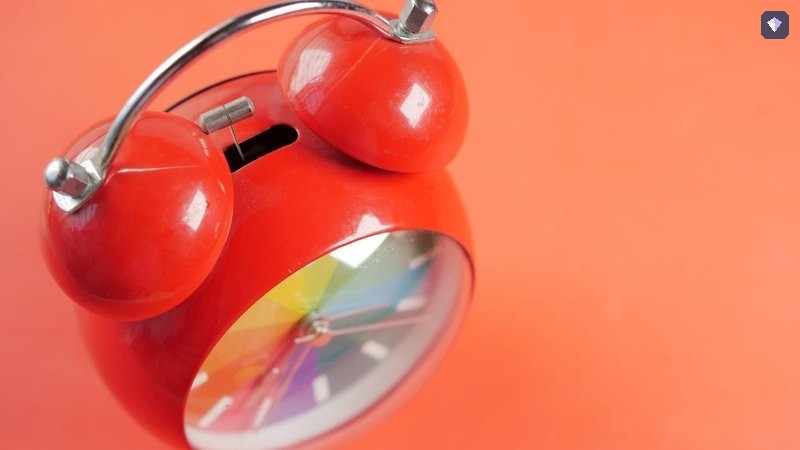 A red alarm clock standing on an orange background