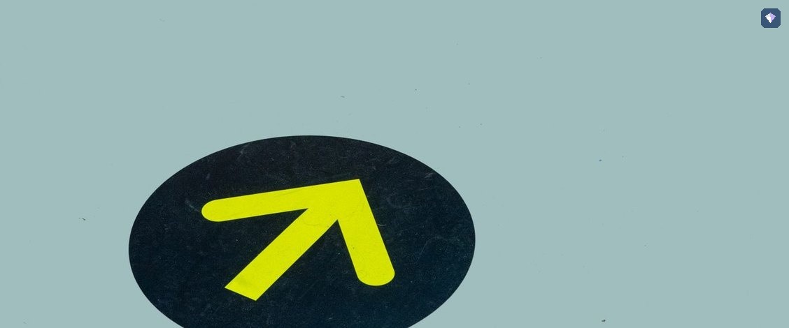 A yellow arrow painted on a blue floor pointing one way