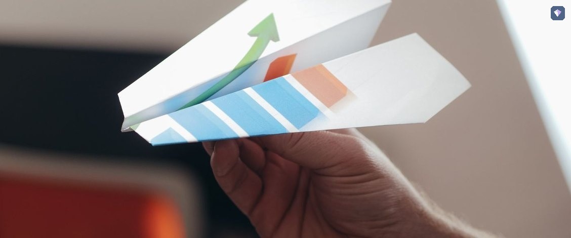 A hand holding a folded paper aeroplane