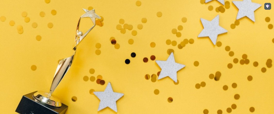 A gold trophy standing among paper stars on a yellow background