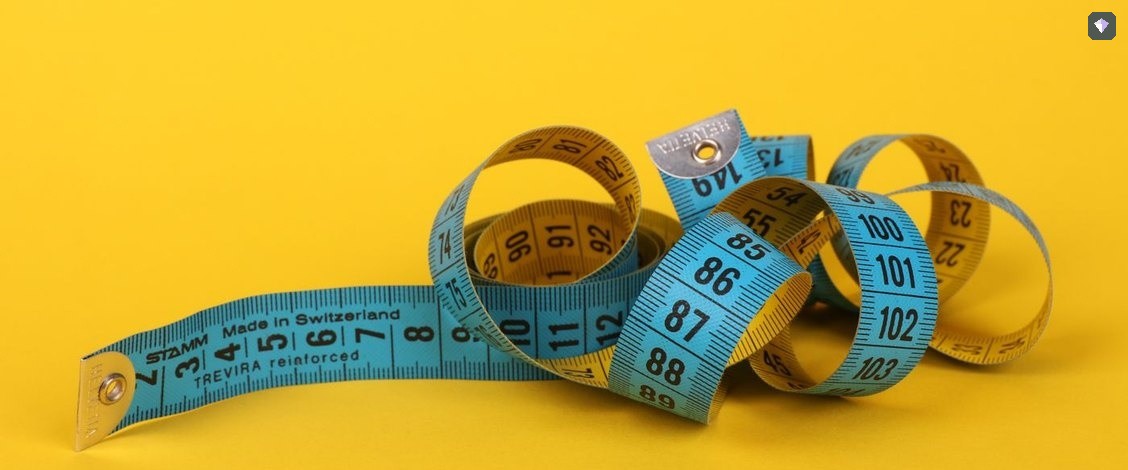 A measuring tape coiled on a bright yellow background