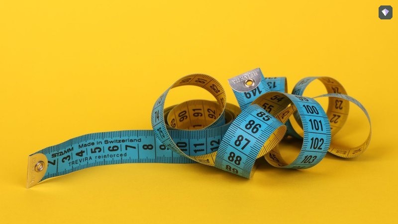 A measuring tape coiled on a bright yellow background