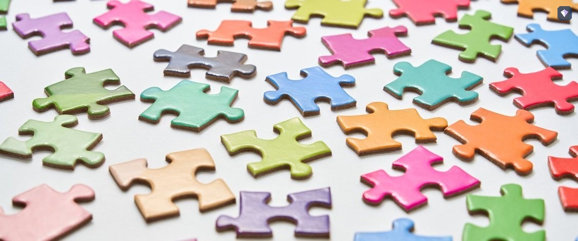 Jigsaw pieces in pastel colours scattered loose on a white surface