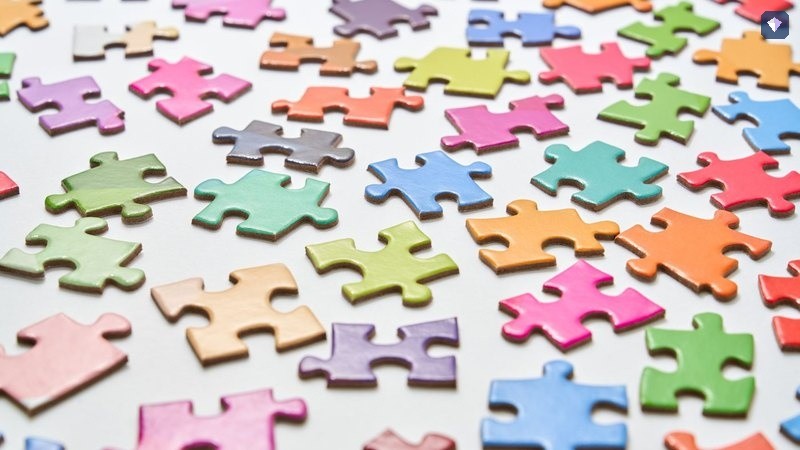 Jigsaw pieces in pastel colours scattered loose on a white surface