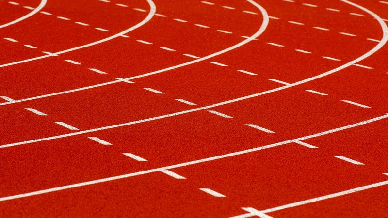 The curved red lanes of an athletics track marked out in white lines and dashes