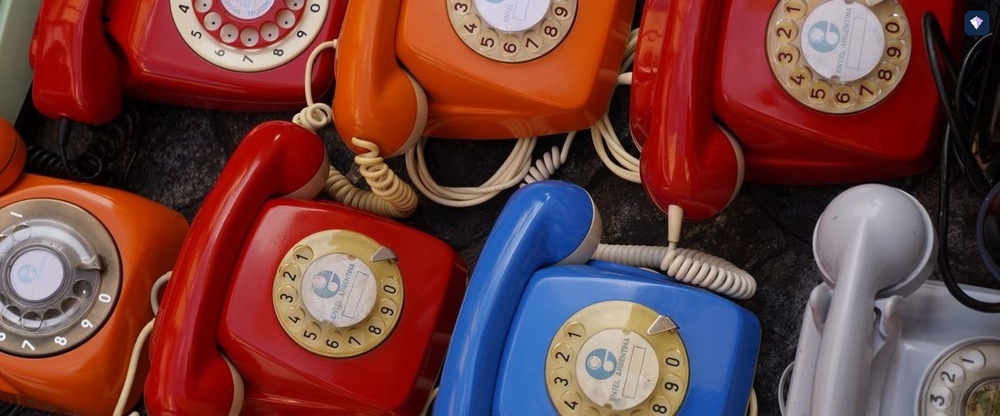 Rotary telephones in red, blue and cream arranged together