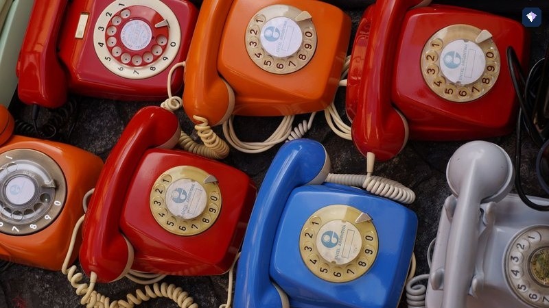 Rotary telephones in red, blue and cream arranged together