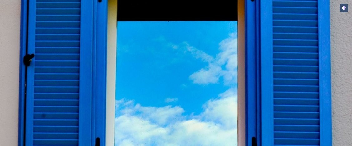 A blue shuttered window standing open to a bright sky