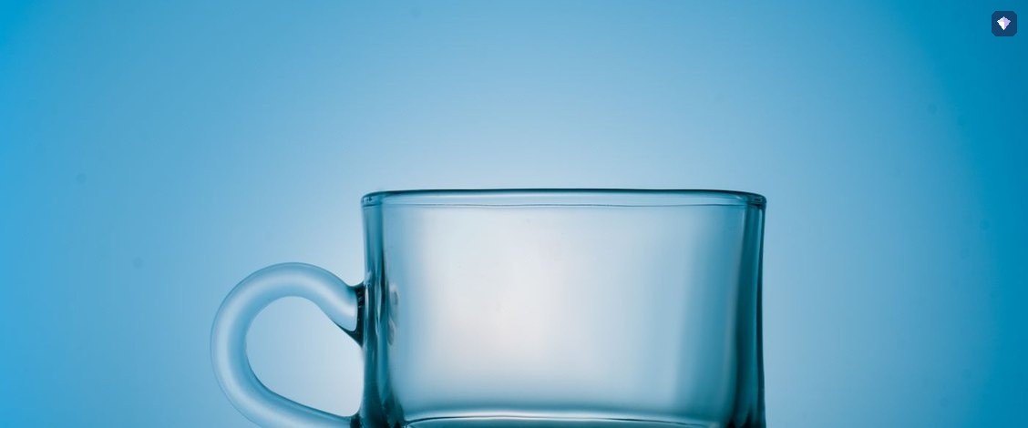 An empty glass cup standing on a blue background