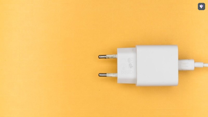 A white plug lying unconnected on a yellow background