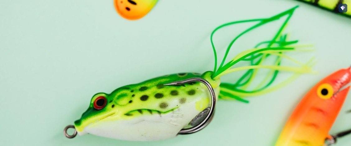Brightly coloured fishing lures laid out on a pale green surface