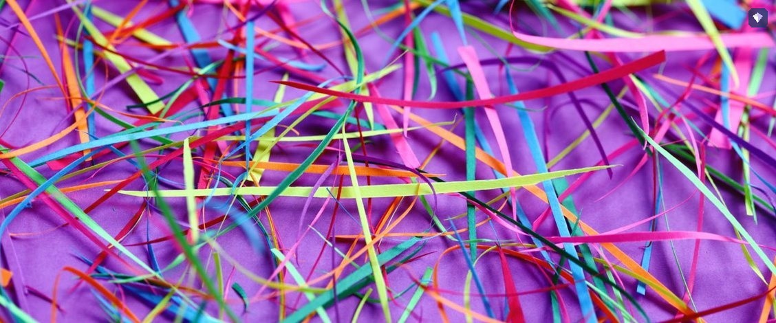 Shredded paper in bright colours scattered on a purple surface