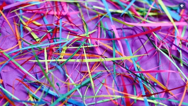 Shredded paper in bright colours scattered on a purple surface