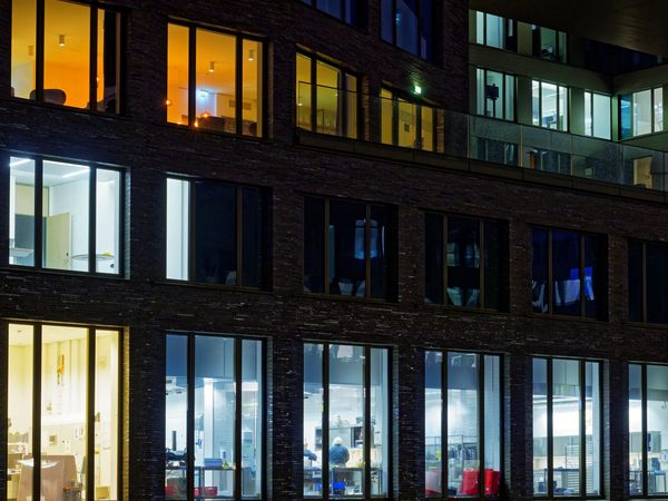An office building at night with its windows lit floor by floor while the street below is dark